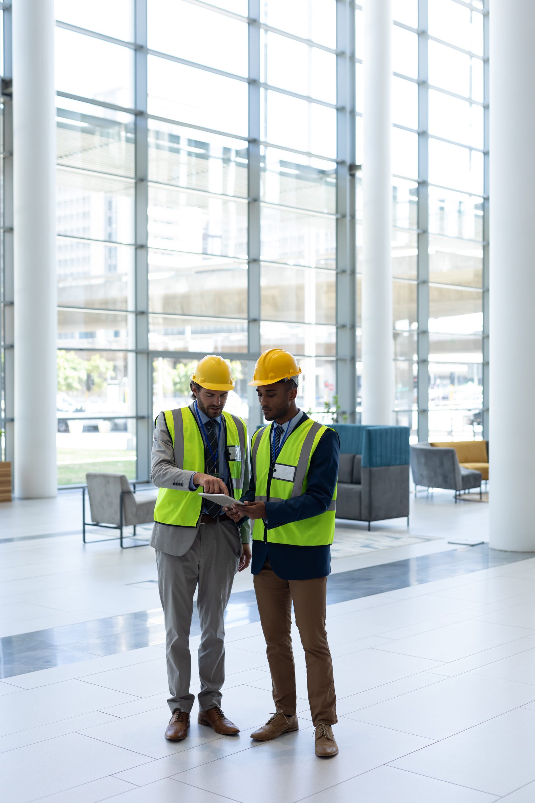 Front view of young multi-ethnic business architect standing and discussing over the digital tablet in lobby at office